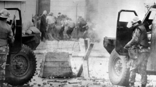 In this January 30, 1972 file photo, soldiers take cover behind their armoured cars in Northern Ireland. A former British soldier is set to be prosecuted in connection with the deaths of two civil rights protesters more than 40 years ago.