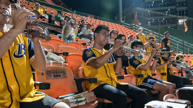 People wearing jerseys of the Chinatrust Brothers baseball team play instruments during a game against Uni-President Lions, at Tainan Stadium, in Tainan, Taiwan.