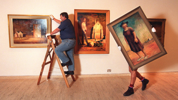 Gallery staff hang paintings by Russell Drysdale (L-R The Cricketers, Picture of Donald Friend and Woman in a Landscape) for a major retrospective at the Art Gallery of NSW on March 25, 1998.