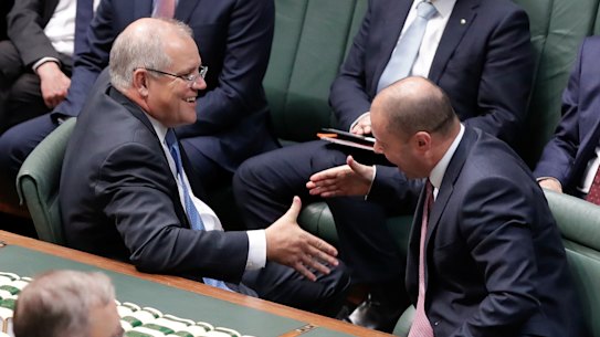 Prime Minister Scott Morrison and Treasurer Josh Frydenberg shake hands after the government’s income tax bill passed the House of Representatives in 2019. But the changes will still mean millions of Australians facing bracket creep.
