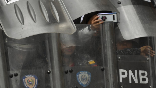 A riot police officer takes a photo while blocking an opposition march in Caracas on Tuesday.