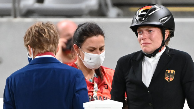 German coach Kim Raisner (centre) and rider Annika Schleu following the incident involving horse Saint-Boy at the Tokyo Olympics.