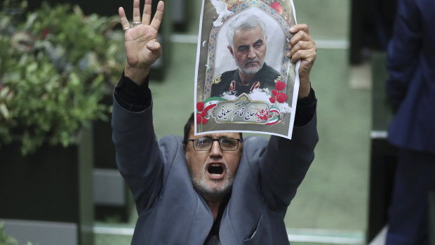 Iranian lawmaker Mohammad Javad Abtahi holds a poster of General Qassem Soleimani as he encourages his colleagues to vote for a bill that declares the  US military's command at the Pentagon and those acting on its behalf "terrorists".