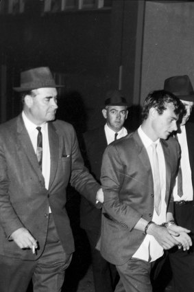 Peter Walker is led in to police headquarters in Sydney after his recapture in January 1966.
