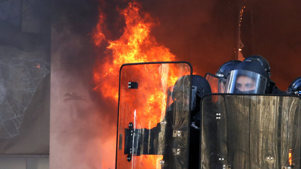 Riot police officers stand in front a burning building during a yellow vests demonstration on Saturday in Paris. 