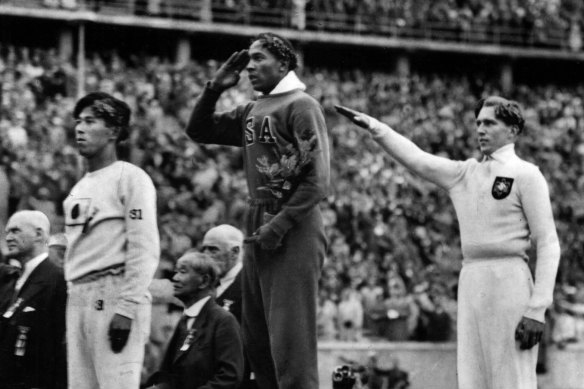 America’s Jesse Owens, centre, salutes during the presentation of his gold medal for the long jump after defeating Nazi Germany’s Luz Long, right, during the 1936 Olympics in Berlin. Naoto Tajima of Japan, left, took bronze. 