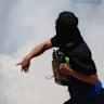A protester in Paramount, Los Angeles, throws a rock amid tear gas from law enforcement during a demonstration after federal immigration authorities conducted operations.