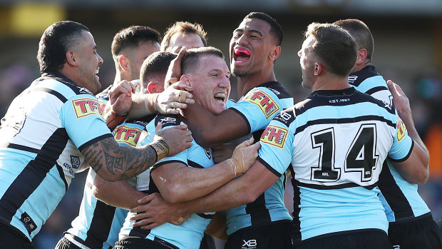Paul Gallen celebrates with teammates after kicking a field goal in the Sharks' victory over the Tigers.