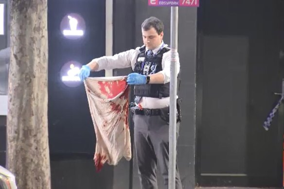 An officer holding a bloodstained shirt at the burger store. 
