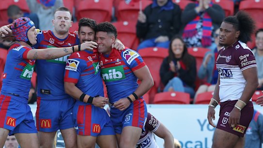 Newcastle players celebrate a try, much to the disdain of their Manly counterparts.