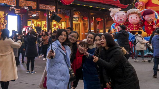 Women take a selfie at the Yu Garden decorated with pig statues for Lunar New Year in Shanghai on Saturday. The latest economic figures show China's middle class is rapidly expanding.