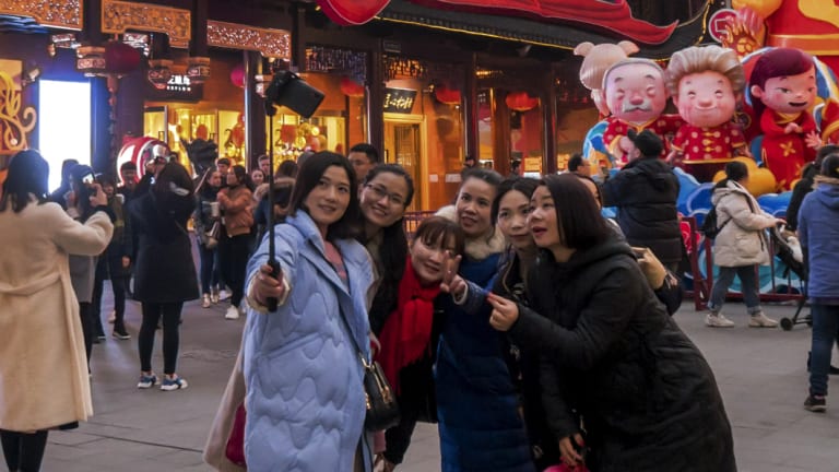 Women take a selfie as others tour at the Yu Garden decorated with pig statues for Lunar New Year in Shanghai on Saturday. The latest economic figures show China's middle class is rapidly expanding.