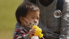 Residents wearing face masks play soap bubbles near a temporary testing centre for COVID-19 in Hong Kong.