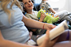 Happy child on airplane journey holding a plush toy while his mother reads.
