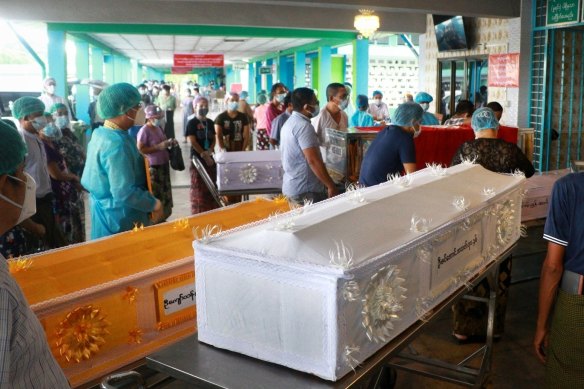 People wait while caskets with the bodies of COVID patients are queued outside a crematorium at the Yay Way cemetery in Yangon, Myanmar.