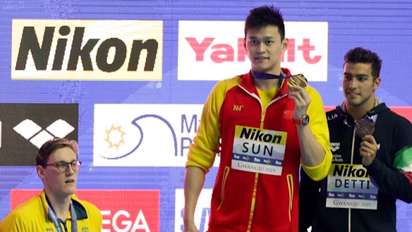 China's Sun Yang, centre, with his gold medal as silver medallist Australia's Mack Horton, left, stands away from the podium.