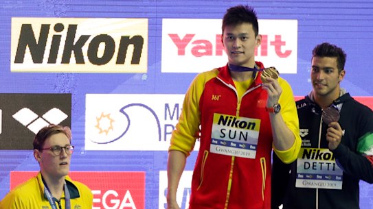 China's Sun Yang, centre, with his gold medal as silver medallist Australia's Mack Horton, left, stands away from the podium.