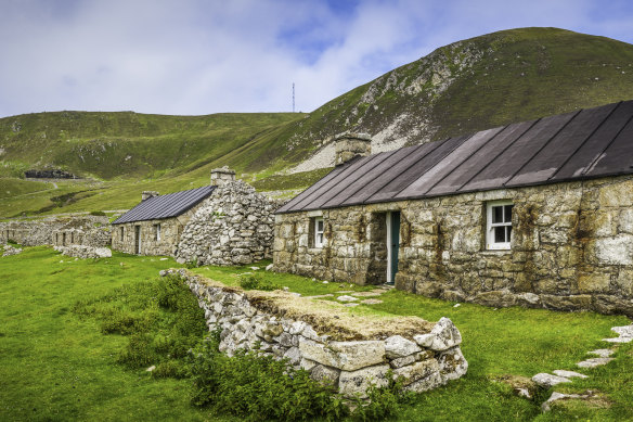 A renovated stone cottage sits among ruins on the remote island of Hirta.