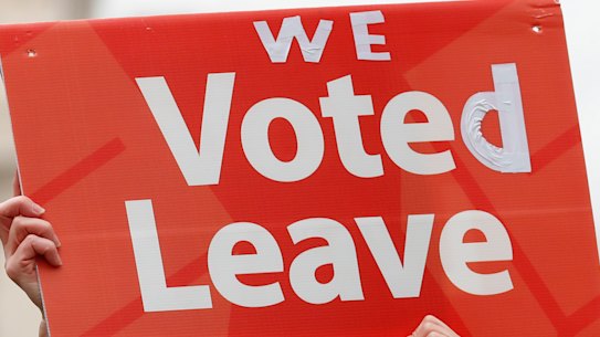 A pro-Brexit demonstrator waves a placard with others outside the Houses of Parliament in London.
