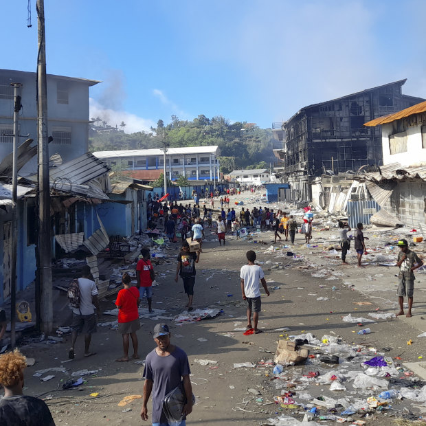 People walk through the looted streets of Chinatown in Honiara on November 26.