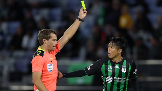 Referee Alex King shows the yellow card to Riku Danzaki during an A-League match in April.