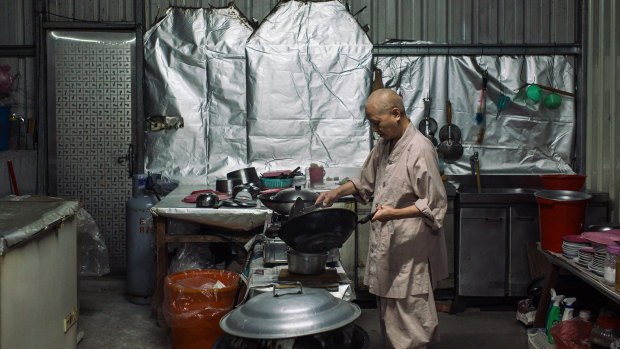 A nun cooks inside a shed that houses Buddhist nuns evicted from their temple in Ershu.