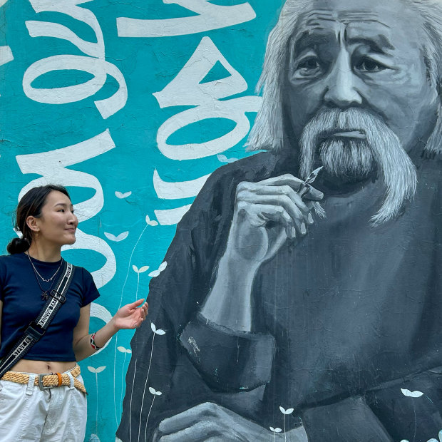 Zolzaya Nyamdorj, a coordinator at Save the Mongolian Language movement, in front of a mural of scholar Renchin Byamba. 