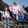 Annabelle Cleeland and her five-year-old daughter Quinn (centre) with Lou Webb (left) and her children Tom and Fred, 3, and George, 6, and Felicity Jeffrey and her children Jemima,6, Sebastien,4 and Claudio,1, stand in the burnt out Jeffrey property in Whiteheads Creek. All three families’ homes were decimated by the Longwood fire.