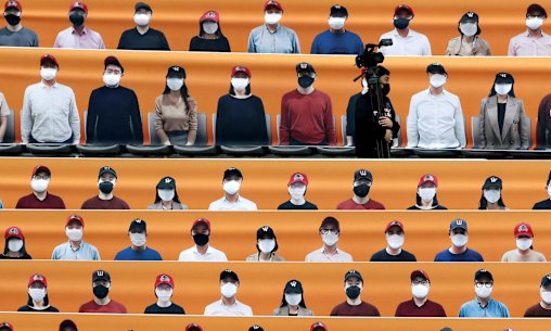 A TV cameraman walks through the spectators' seating which are covered with pictures of fans, before the start of a regular season baseball game between Hanwha Eagles and SK Wyverns in Incheon, South Korea, Tuesday, May 5, 2020. South Korea's professional baseball league start its new season on May 5, initially without fans, following a postponement over the coronavirus. (AP Photo/Lee Jin-man)