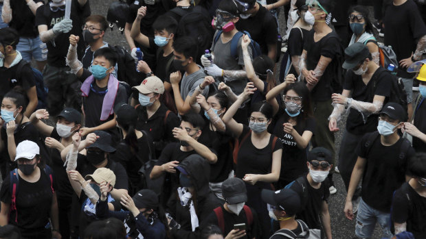 Protesters make the gestures of holding umbrellas during a protest in Hong Kong on Monday.