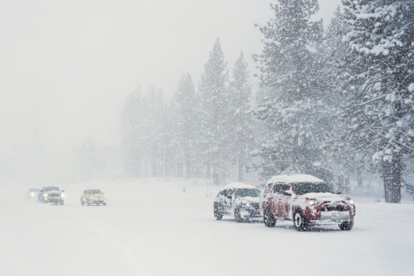 Motoristas dirigem em uma estrada coberta de neve durante uma tempestade em Truckee, Califórnia.