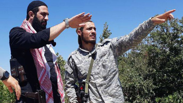 This undated file photo released by the militant group Levant Liberation Committee on  August  21, shows Abu Mohammed al-Golani of the militant Levant Liberation Committee and the leader of Syria's al-Qaida affiliate, left, talking with a fighter, in the countryside of Latakia, Syria. 