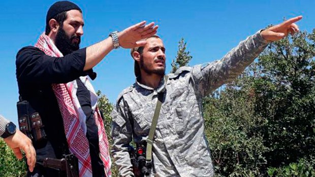 This undated file photo released by the militant group Levant Liberation Committee on  August  21, shows Abu Mohammed al-Golani of the militant Levant Liberation Committee and the leader of Syria's al-Qaida affiliate, left, talking with a fighter, in the countryside of Latakia, Syria. 