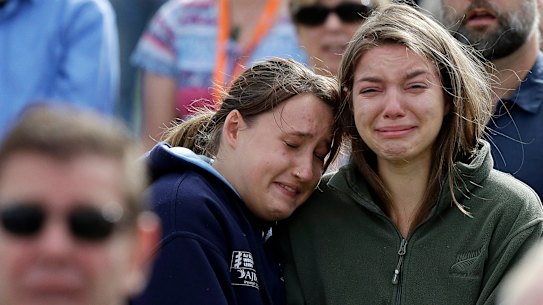 Two members of the crowd as the New Zealand national anthem is sung during a national remembrance service. 