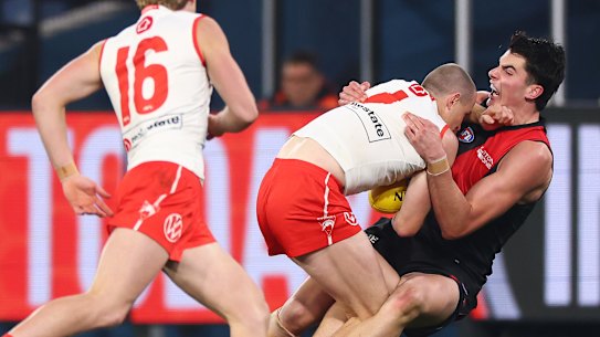 Cop that: An Essendon player feels the brunt of Sydney’s Chat Warner.