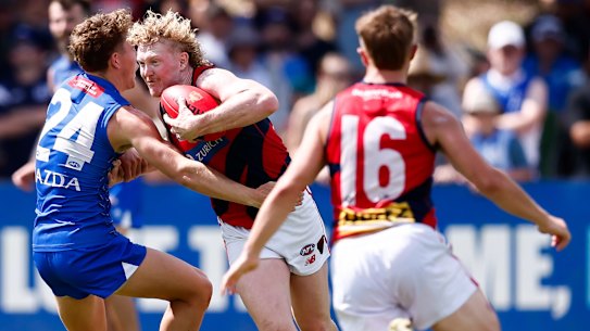 Clayton Oliver looks to burst through two opponents.