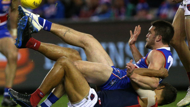 Flat out: Bailey Williams gets boot to ball after being taken down by Demon Neville Jetta.