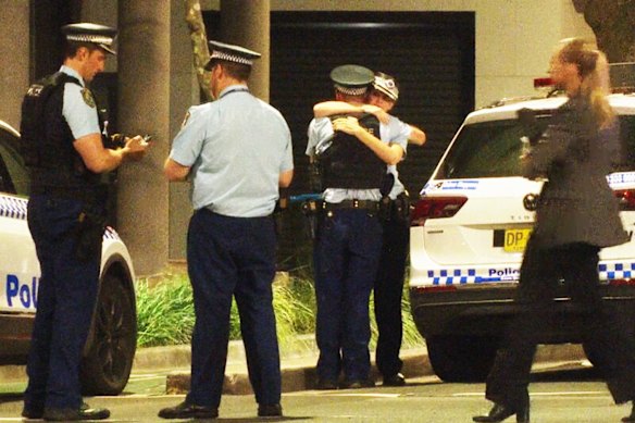 Police comfort one another after a female constable died in a crash in inner Sydney.