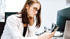 oung Businesswoman sitting at her desk in modern office checking the news on her mobile phone, looking worried, confused and angry reading the bad news. Real People Office Scene. . Photo: iStock