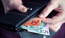 Adult woman female hand pulling out Australian money from a leather wallet.