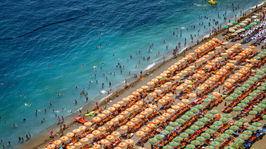 Aerial photography of tourists playing and taking sunbath on a sandy beach in Positano, Italy.