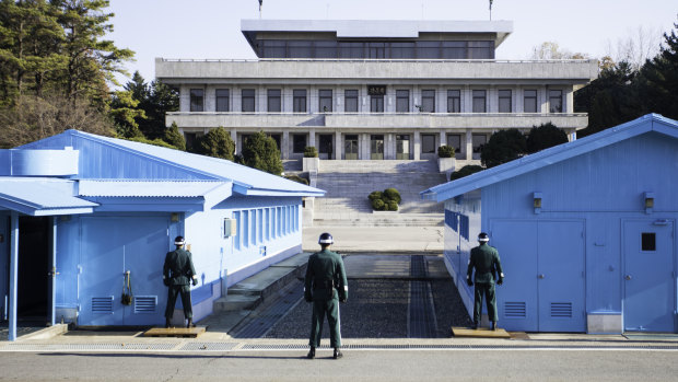 South Korean soldiers guard the border between South and North marked by a short concrete wall in the DMZ. 