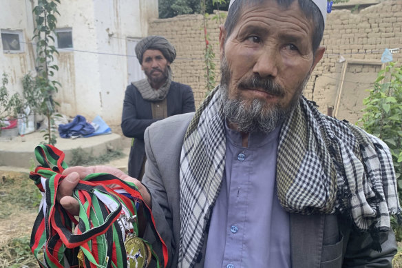 Mohammed Jan Sultani’s father, Ali, holds his son’s awards. Mohammed had clutched his national Taekwondo championship certificates as he pushed to get into Kabul airport late last week. 