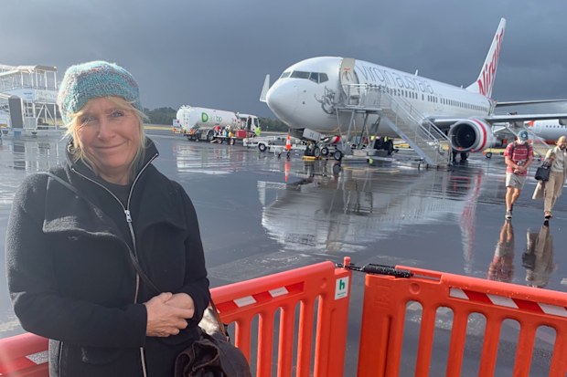 A woman standing on the tarmac at an airport, Virgin plane behind her