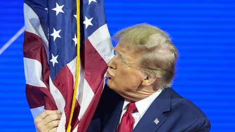 Donald Trump hugs and kisses the American flag at the Conservative Political Action Conference.
