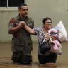 A soldier helps a woman evacuate from a neighbourhood in Canoas flooded by heavy rain.