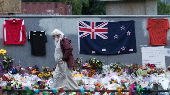 A Muslim man walks past a makeshift memorial on the walls surrounding the Al Noor Mosque following the Christchurch attack.