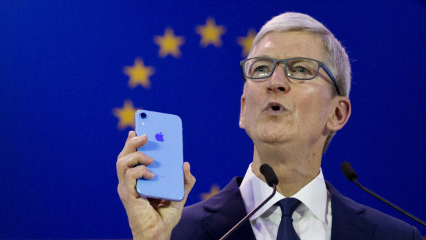 Apple boss Tim Cook holds up an iPhone as he speaks during a data privacy conference in Brussels.