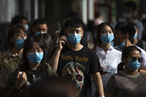 People wearing face masks to protect against the spread of the new coronavirus walk along a pedestrian shopping street in Beijing, Saturday, May 16, 2020. 