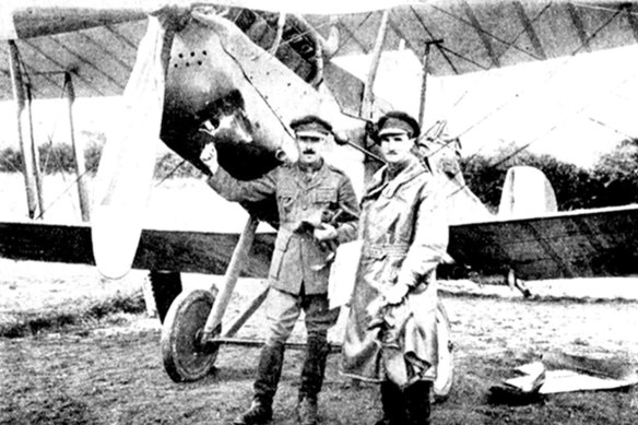 Captain Youdale is seen pointing to a hole in his biplane caused by a shell. On a previous flight he returned with 30 bullet holes.